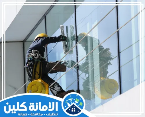 تنظيف زجاج النوافذ بالقطيف 0535521559 شركة الأمانة كلين تنظيف زجاج النوافذ بالقطيف يتطلب مهارة ومعدات خاصة، كما يظهر في هذه الصورة التي تُظهر عاملاً وهو معلق لتنظيف الواجهة الزجاجية لمبنى شاهق